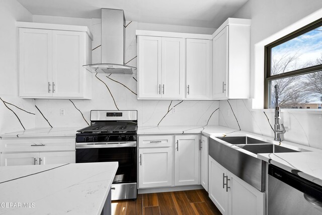 kitchen featuring wall chimney range hood, stainless steel appliances, dark hardwood / wood-style floors, light stone countertops, and white cabinets