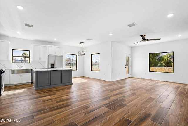 kitchen featuring stainless steel refrigerator with ice dispenser, hanging light fixtures, gray cabinets, a kitchen island, and white cabinets