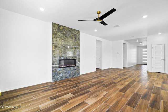 unfurnished living room featuring ceiling fan and a tile fireplace