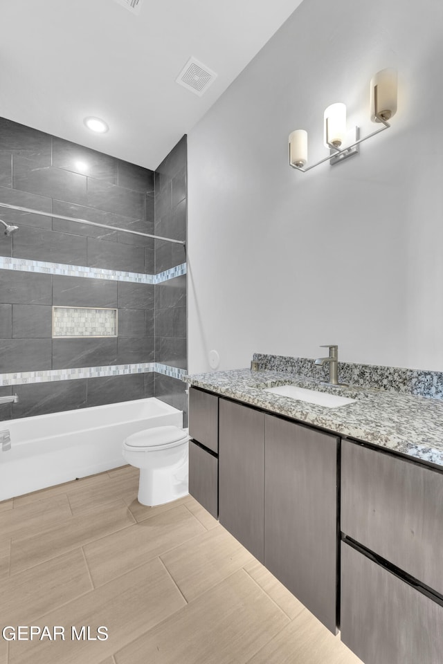 full bathroom with vanity, tiled shower / bath combo, and toilet