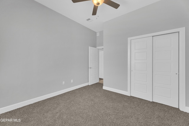 unfurnished bedroom featuring vaulted ceiling, dark colored carpet, ceiling fan, and a closet