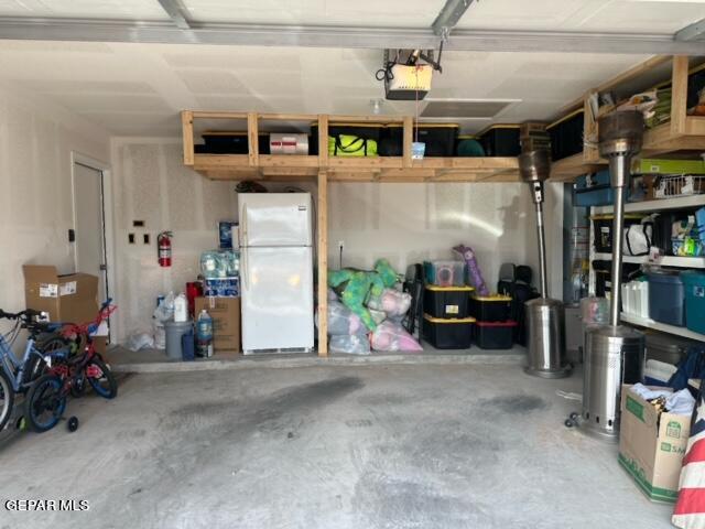 garage with a garage door opener and white refrigerator