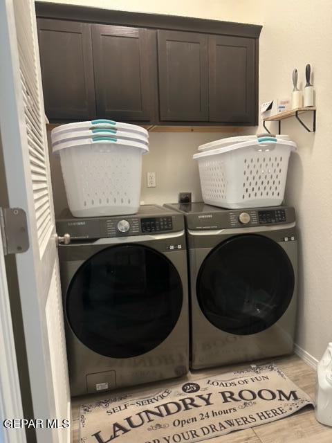 laundry room featuring light wood-type flooring, washer and clothes dryer, and cabinets