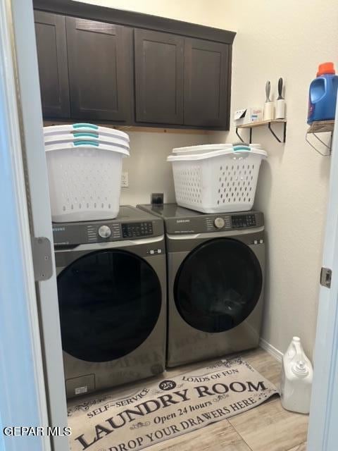 laundry area with cabinets, light wood-type flooring, and washer and dryer