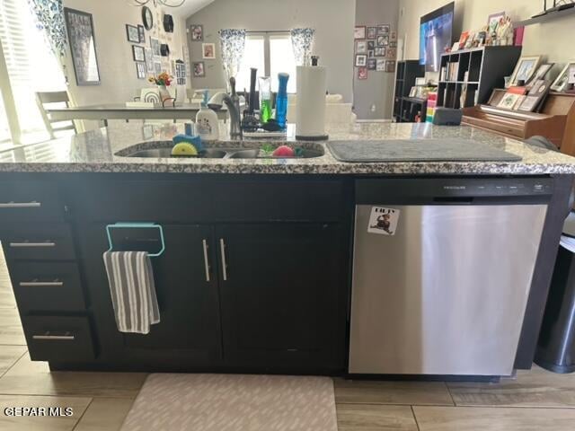 kitchen featuring light stone counters, a center island with sink, sink, and stainless steel dishwasher