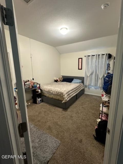 carpeted bedroom featuring lofted ceiling and a textured ceiling