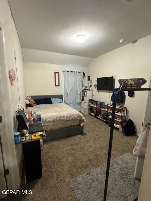 carpeted bedroom with a textured ceiling and vaulted ceiling