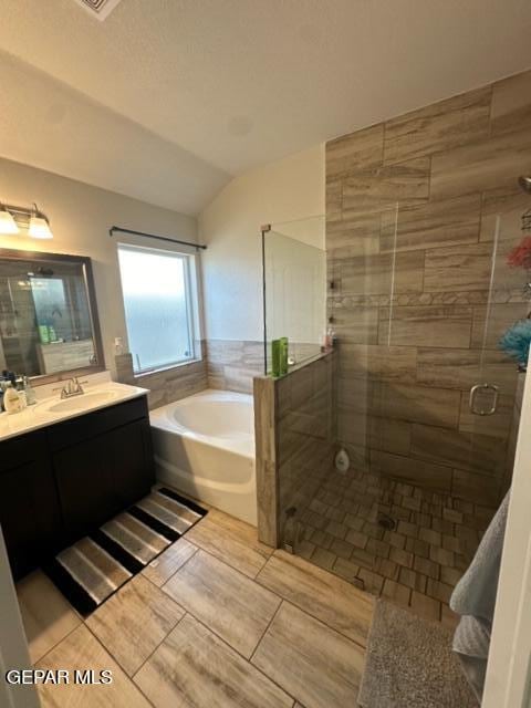 bathroom featuring tile patterned floors, vaulted ceiling, vanity, and separate shower and tub