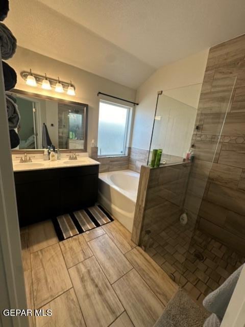 bathroom with vanity, separate shower and tub, and vaulted ceiling