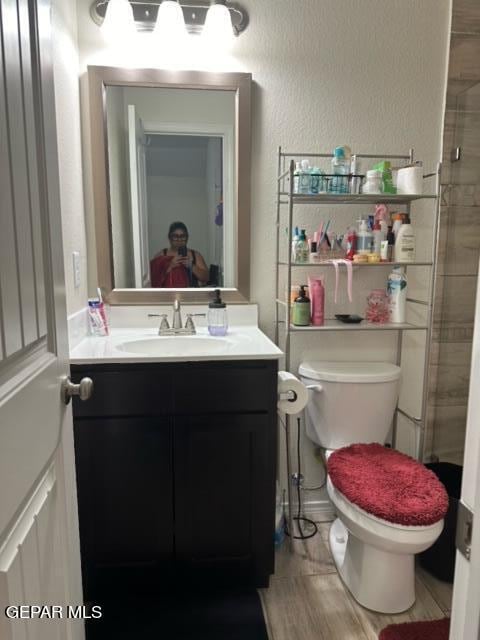 bathroom featuring a tile shower, vanity, and toilet