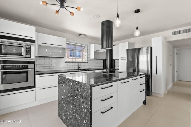 kitchen featuring a center island, white cabinets, backsplash, appliances with stainless steel finishes, and decorative light fixtures