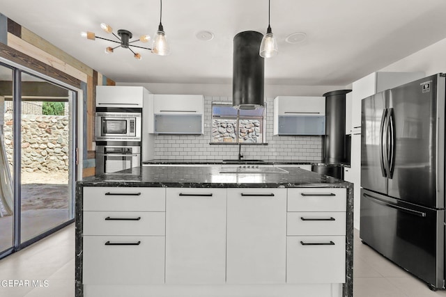 kitchen with dark stone counters, tasteful backsplash, white cabinets, appliances with stainless steel finishes, and decorative light fixtures