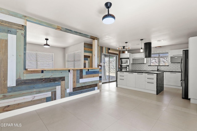 kitchen with tasteful backsplash, white cabinets, appliances with stainless steel finishes, light tile patterned floors, and decorative light fixtures