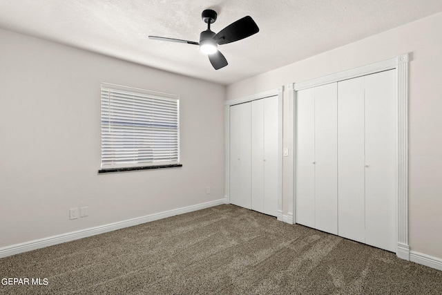 unfurnished bedroom featuring two closets, carpet, ceiling fan, and a textured ceiling