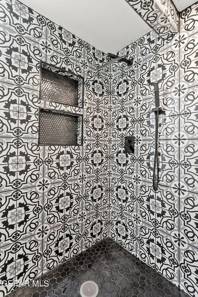 bathroom with a textured ceiling and a tile shower