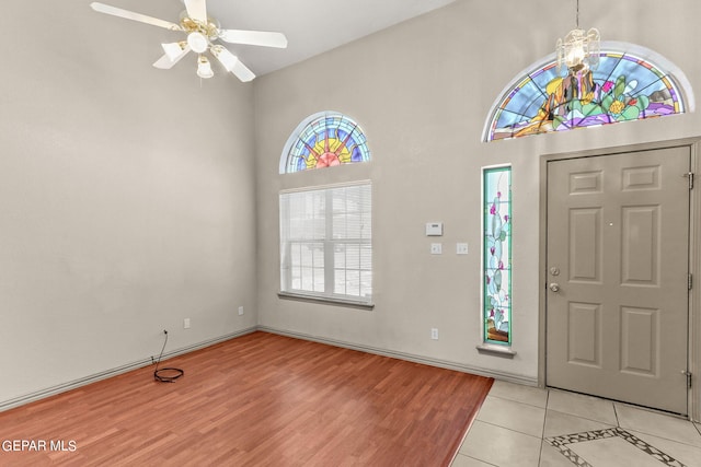 foyer with a towering ceiling, light hardwood / wood-style floors, and ceiling fan