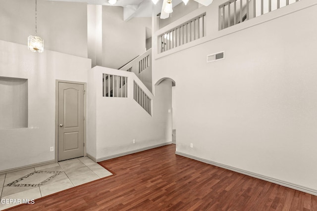 interior space featuring a high ceiling, wood-type flooring, and ceiling fan