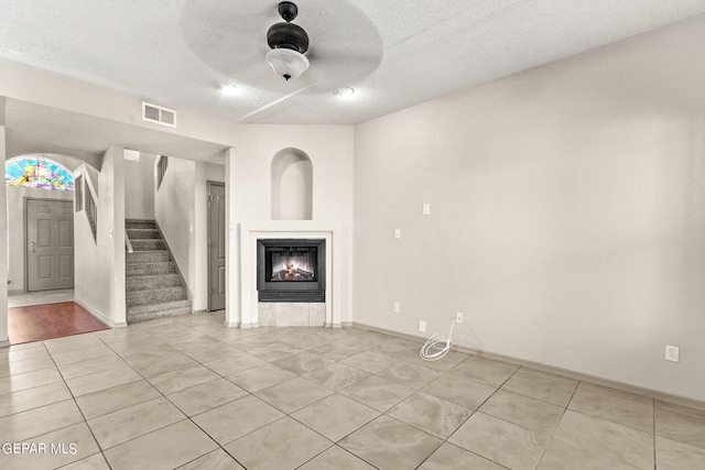 unfurnished living room with ceiling fan, a textured ceiling, and light tile patterned floors