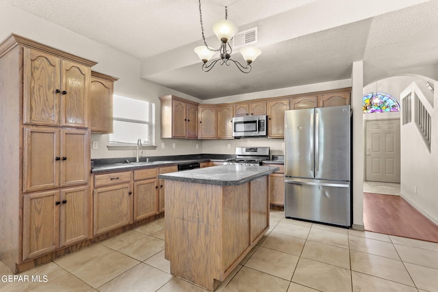 kitchen featuring a kitchen island, pendant lighting, stainless steel appliances, a textured ceiling, and a chandelier