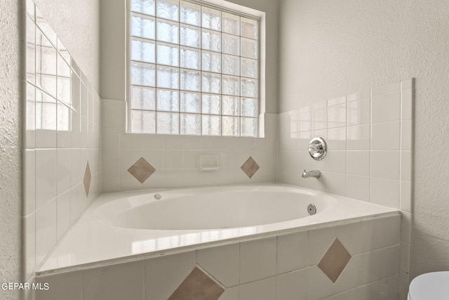 bathroom with tiled tub and toilet