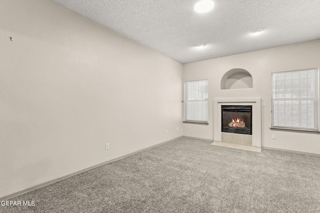 unfurnished living room with a textured ceiling, carpet floors, and a healthy amount of sunlight