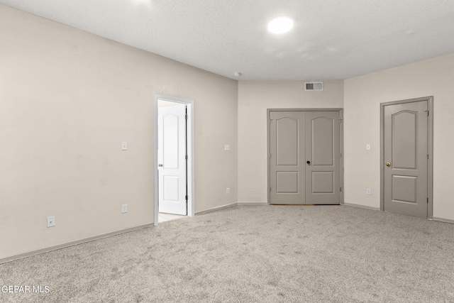 interior space with a textured ceiling and light carpet