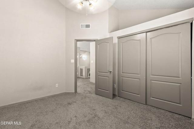 unfurnished bedroom featuring light colored carpet, a closet, and vaulted ceiling