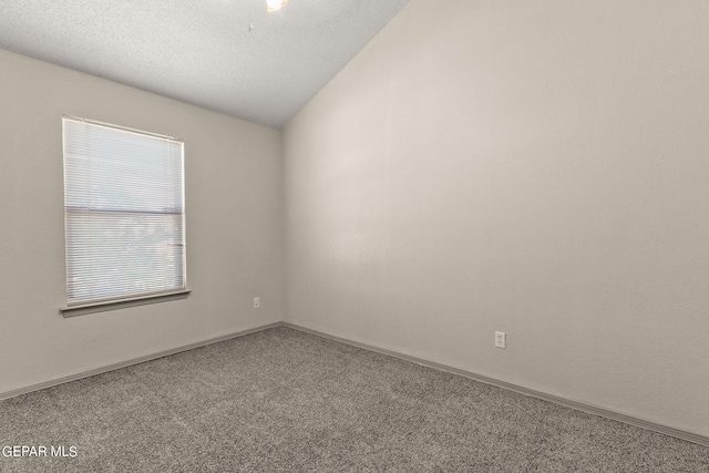 carpeted spare room featuring a textured ceiling and vaulted ceiling