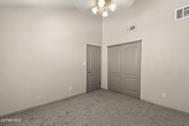 unfurnished bedroom with ceiling fan, high vaulted ceiling, light colored carpet, and a closet