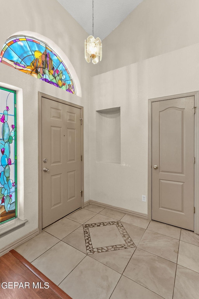 foyer with light tile patterned floors, a notable chandelier, and vaulted ceiling