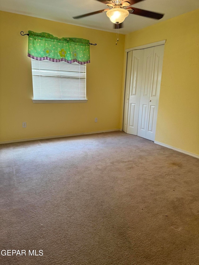 unfurnished bedroom featuring carpet floors, ceiling fan, and a closet