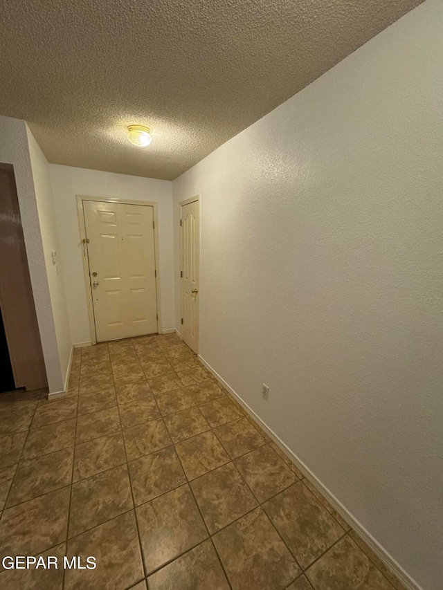 corridor featuring a textured ceiling and tile patterned flooring