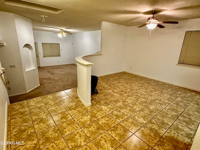 basement featuring ceiling fan, carpet floors, and a textured ceiling