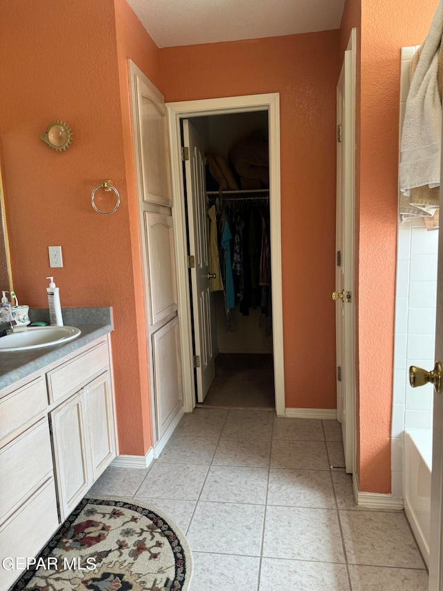 bathroom with tile patterned floors, a tub, and vanity