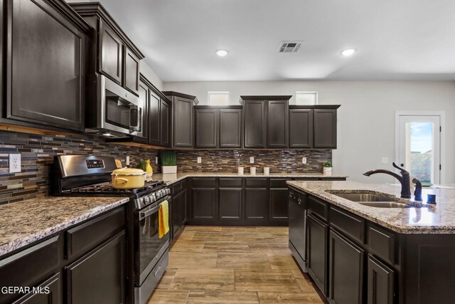 kitchen with appliances with stainless steel finishes, light hardwood / wood-style floors, sink, and tasteful backsplash