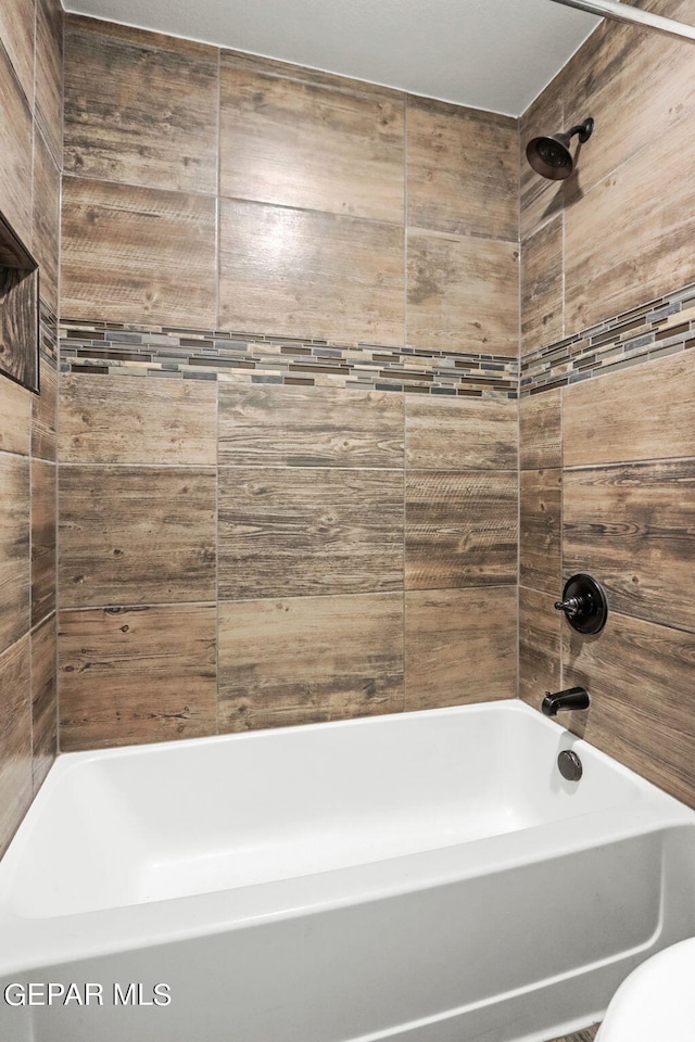 bathroom featuring tiled shower / bath and toilet