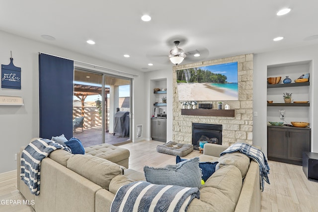 living room featuring light hardwood / wood-style floors, a fireplace, ceiling fan, and built in features