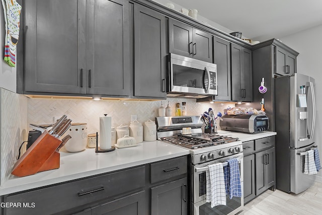 kitchen featuring appliances with stainless steel finishes, backsplash, and light hardwood / wood-style flooring