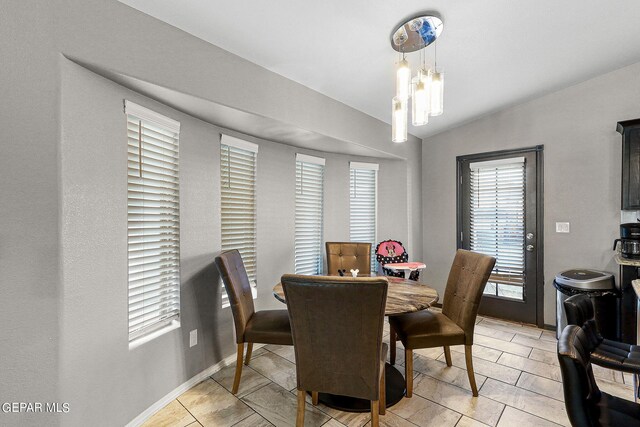 dining area featuring light tile patterned floors, vaulted ceiling, and a chandelier