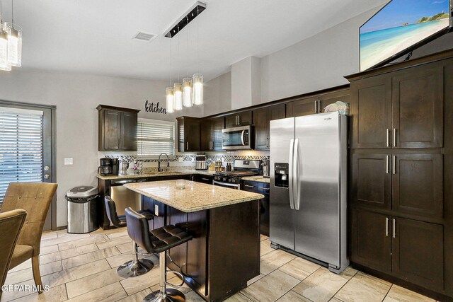 kitchen with appliances with stainless steel finishes, hanging light fixtures, a center island, and a healthy amount of sunlight