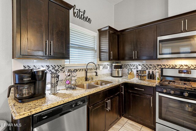 kitchen featuring dark brown cabinets, light stone counters, tasteful backsplash, sink, and stainless steel appliances