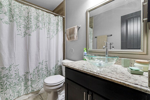 bathroom with walk in shower, vanity, and toilet