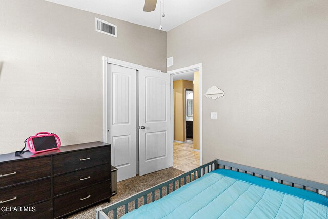 bedroom featuring light carpet, ceiling fan, and a closet