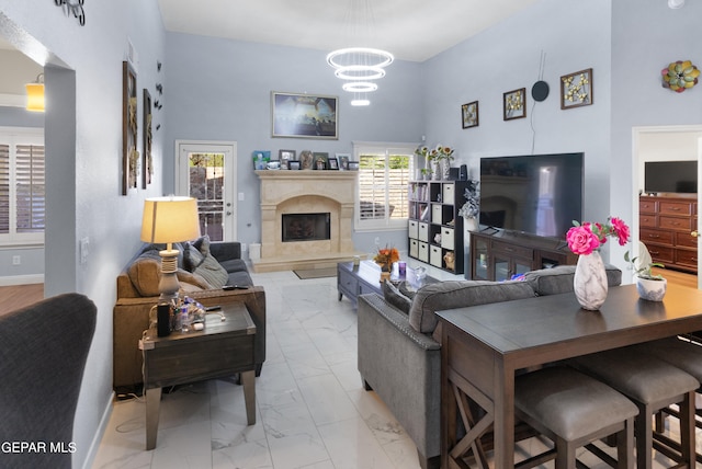 living room featuring a high ceiling, a fireplace, and an inviting chandelier