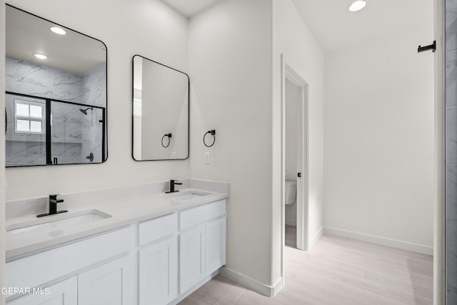 bathroom with wood-type flooring, vanity, toilet, and a shower with shower door