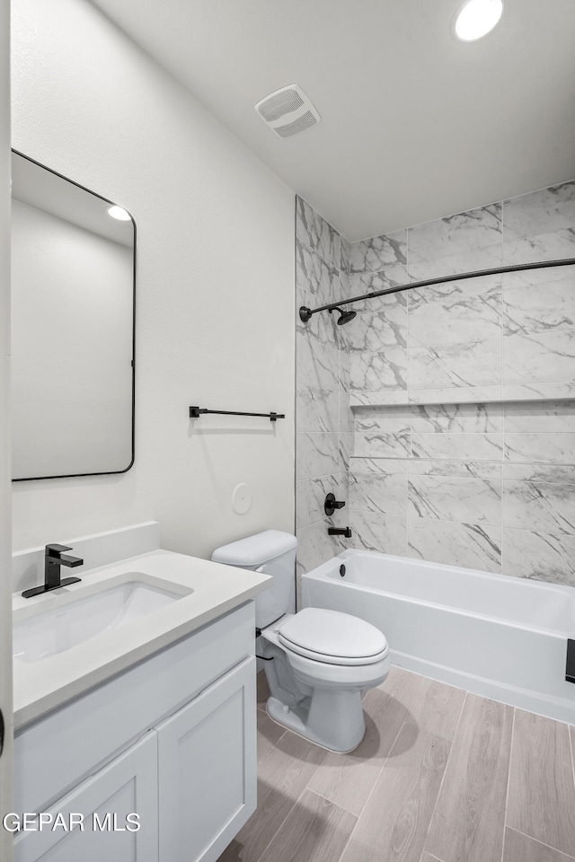 full bathroom with tiled shower / bath combo, vanity, toilet, and hardwood / wood-style flooring