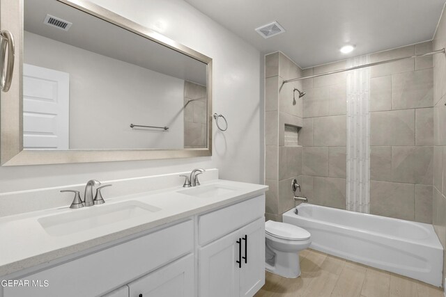 full bathroom with tiled shower / bath combo, vanity, and toilet