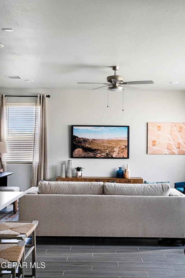 living room featuring ceiling fan and dark hardwood / wood-style floors