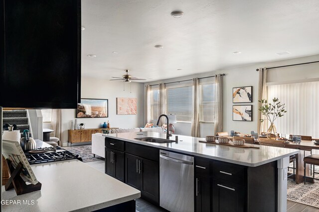 kitchen with dishwasher, light hardwood / wood-style flooring, ceiling fan, a center island with sink, and sink