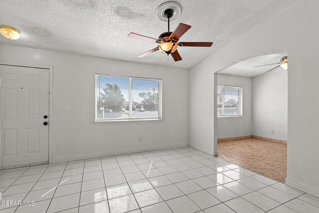 tiled empty room featuring a textured ceiling and ceiling fan